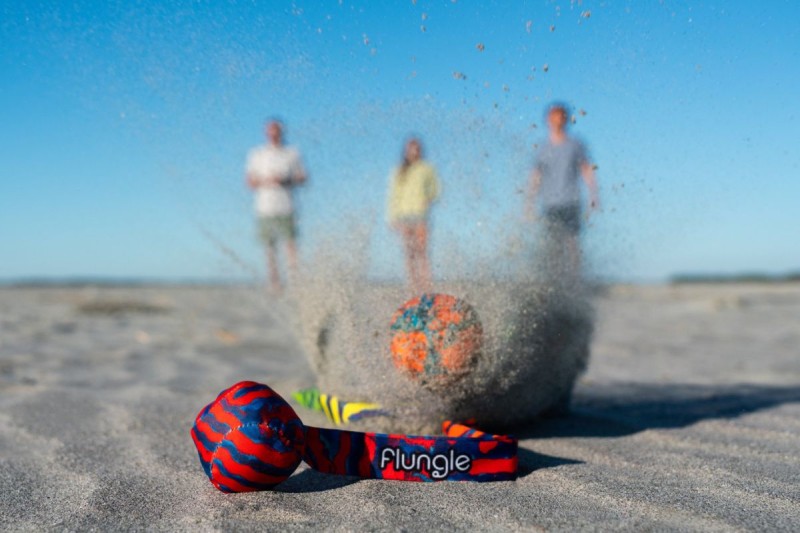 Dziecko rzuca piłką z ogonem Flungle na plaży