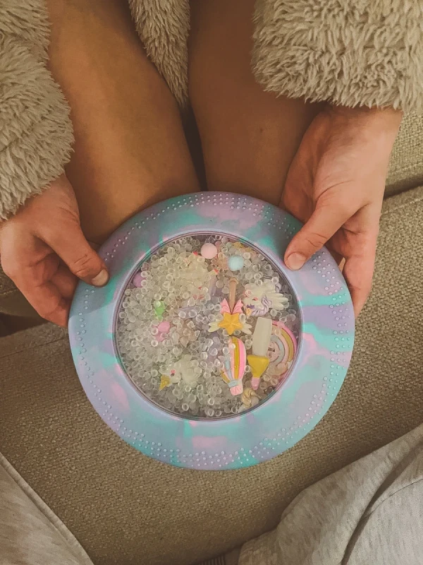 Dysk sensoryczny Jellystone Peekaboo Jednorożec w dłoniach dziecka