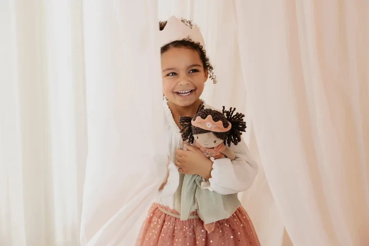 Dziecko trzyma lalkę Princess Evi Little Dutch przy zasłonie
