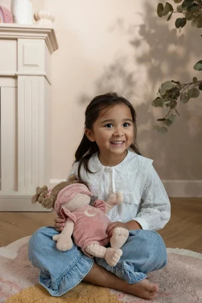 Dziewczynka siedzi z lalką Rosa Little Dutch w pokoju dziecięcym