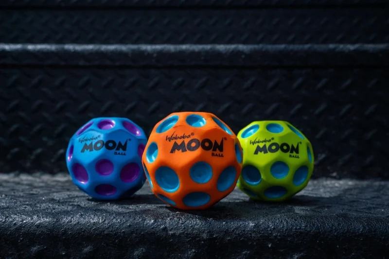 Trzy piłeczki Waboba Moon Ball w różnych kolorach na schodach porównanie wariantów kolorystycznych