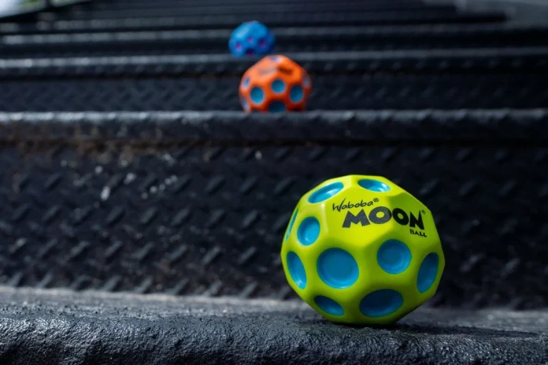 Zielona piłeczka Moon Ball Waboba na schodach podczas zabawy na świeżym powietrzu