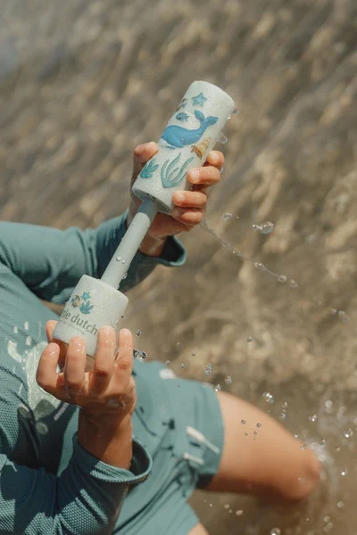 dziecko bawi się pistoletem na wodę little dutch na plaży