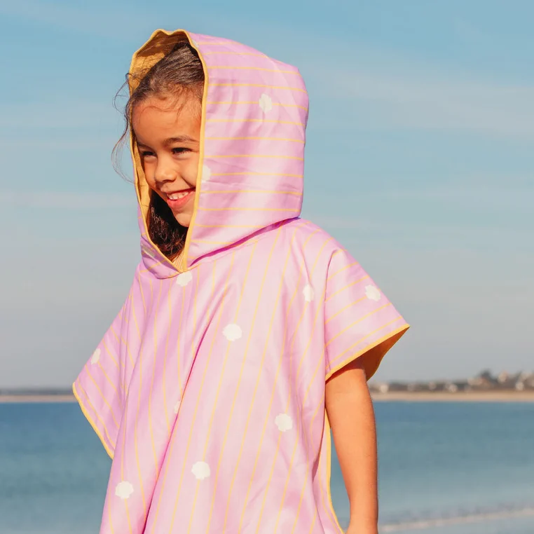Dziewczynka w poncho plażowym QUUT Banana Pink nad morzem