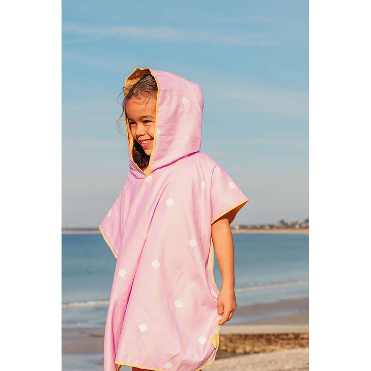 Dziewczynka w różowym poncho kąpielowym QUUT Banana Pink na plaży