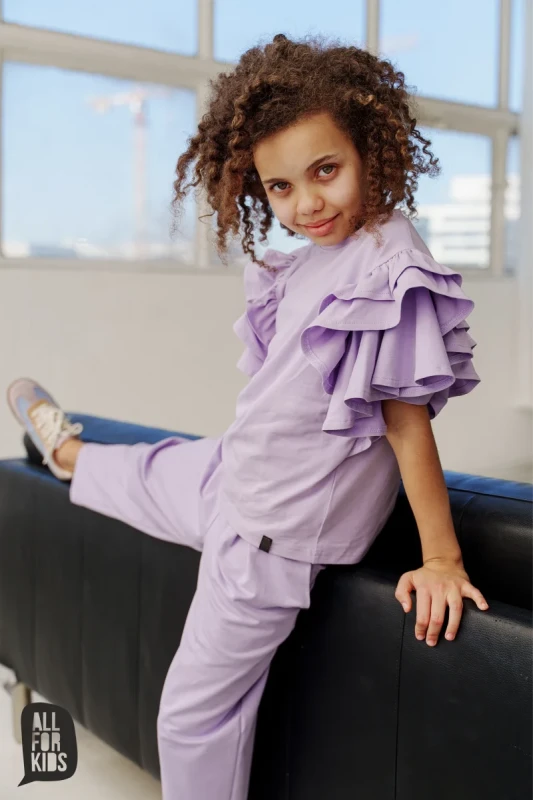Dziewczynka w lawendowych spodniach dresowych i bluzce z falbankami