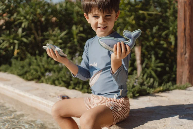 Dziecko trzyma zabawki do nurkowania Little Dutch Ocean World przy basenie