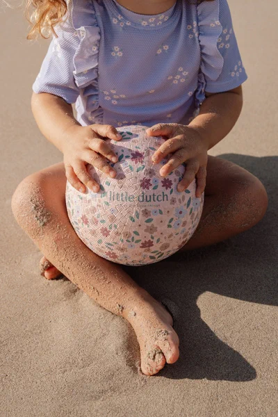 Piłka Little Dutch Dreamy Mermaid w dłoniach dziecka podczas zabawy na piasku