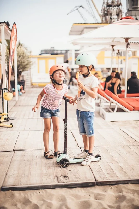 Dziecko w kasku Scoot&Ride Kiwi podczas jazdy na hulajnodze