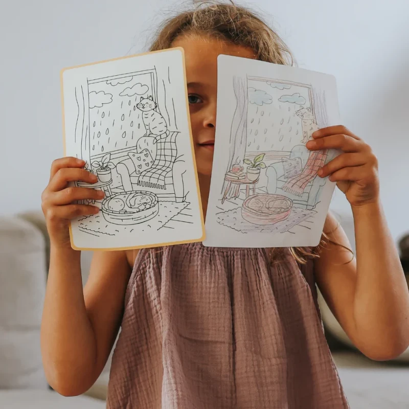 Dziecko pokazujące odrysowaną ilustrację kotów KIDYDRAW PAD Pets